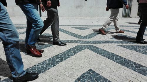 Low section of men standing on tiled floor