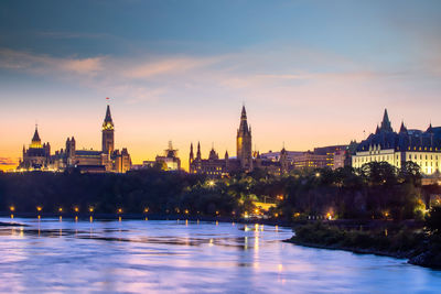 Illuminated buildings in city at sunset