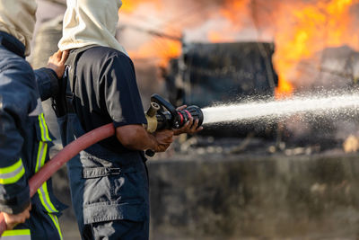 Fireman or firefighter spraying water from big water hose to prevent fire