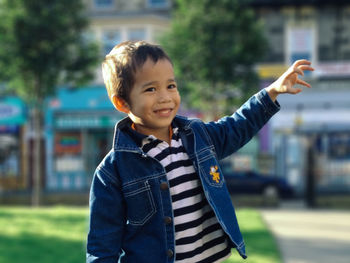 Close-up of happy boy gesturing while standing against buildings