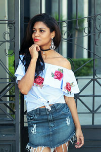 Beautiful young woman standing against wall