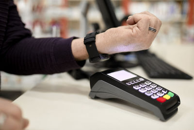 Man making contactless payment through smart watch at checkout counter in store