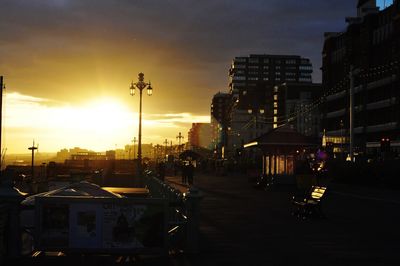 Cars on illuminated city against sky during sunset