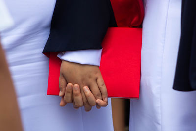 Midsection of people holding hands and books