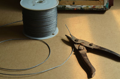 High angle view of steel cables and wire cutter on table in workshop