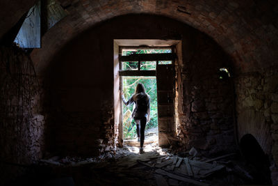 Rear view of woman standing in abandoned building