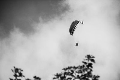 Low angle view of man paragliding against sky