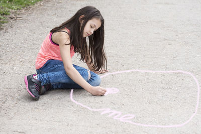 Full length of girl drawing on footpath