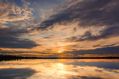 Scenic view of lake against dramatic sky during sunset