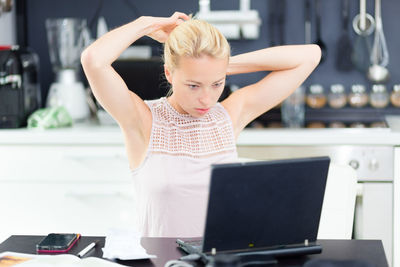 Mid adult woman using laptop sitting at home