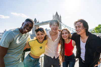 Portrait of smiling friends standing against sky