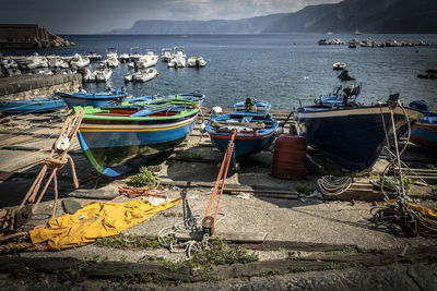 Boats moored at harbor against sky