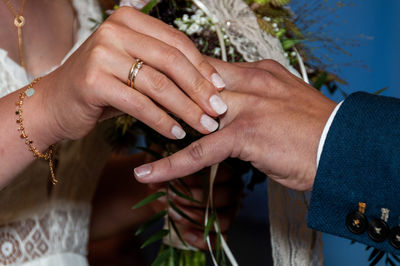 Midsection of bride holding groom finger