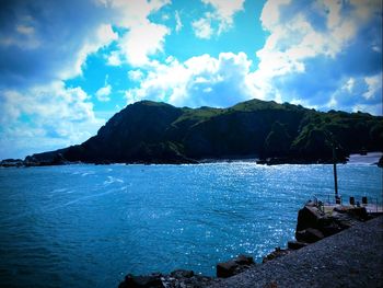 Scenic view of sea and mountains against sky