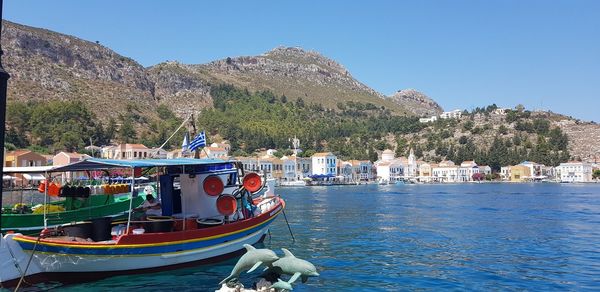 Boats moored in lake against clear blue sky