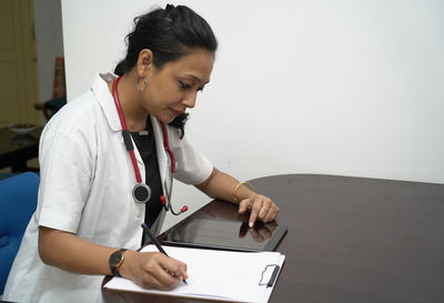 Young woman using mobile phone while sitting on table