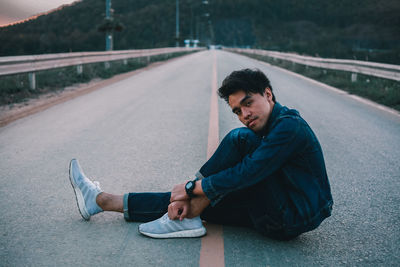 Portrait of young man sitting on road