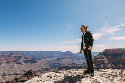 Man standing on rock against sky