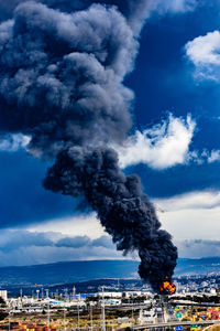 Smoke emitting from sea against sky