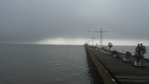 Pier over sea against cloudy sky