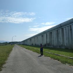 Rear view of man walking on road against sky