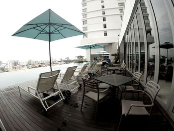 Empty chairs and tables in restaurant against sky