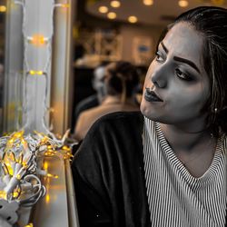 Thoughtful young woman looking through window while sitting in cafe