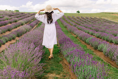 Close up of beautiful smiling woman in hat enjoying summer in lavender field 