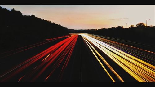 Light trails on road against sky at night