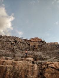 Man on rock formation against sky