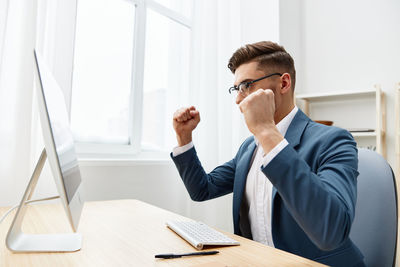Businessman gesturing by looking at desktop pc in office