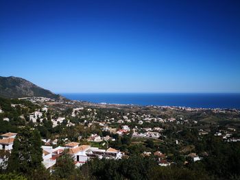 Townscape by sea against clear blue sky