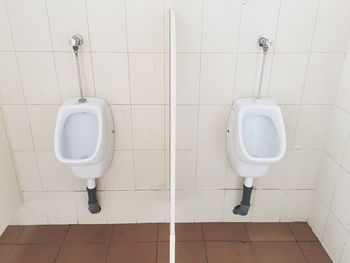 Flushing toilets against tile wall in bathroom