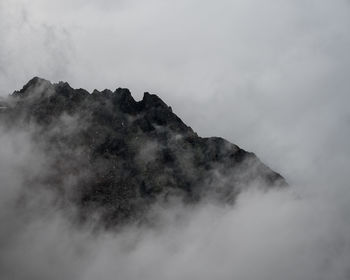 Low angle view of fog covered mountain against sky