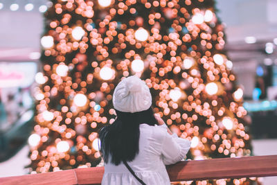 Rear view of woman by illuminated lights in mall