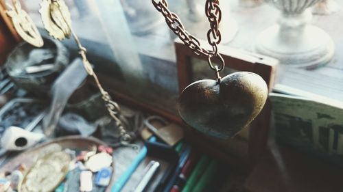 Close-up of heart shape chain against blurred objects on table