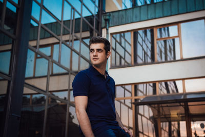 Portrait of young man standing against railing