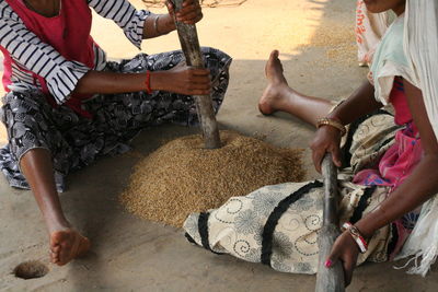 Two women hand pounding grains of rice in a tribal village