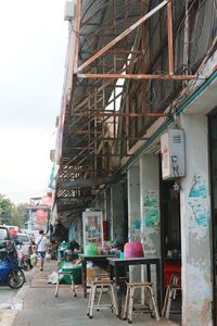 Chairs and tables in cafe against sky in city