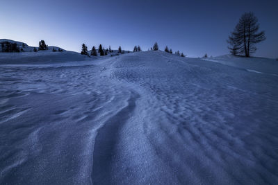 Shapes created by the wind in the snow in a blue morning in cortina d'ampezzo, in the dolomites.