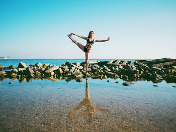 Woman doing yoga at beach against sky