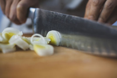 Cropped image of woman cutting scallions in kitchen