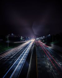 Light trails on road against sky at night