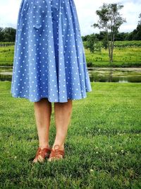 Low section of woman standing on grassy field