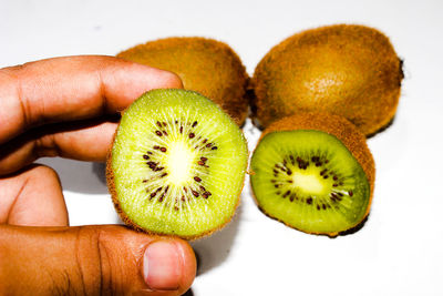 Close-up of hand holding fruits against white background