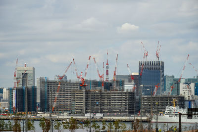 Cranes at construction site against sky in city