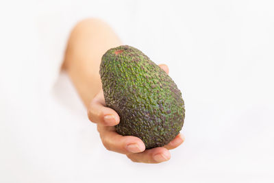Close-up of hand holding fruit against white background