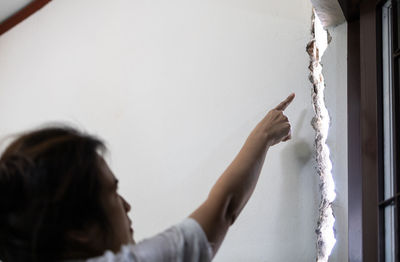 Portrait of woman holding hands against wall at home