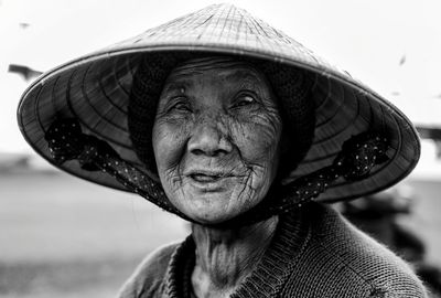 Close-up portrait of senior woman wearing asian style conical hat