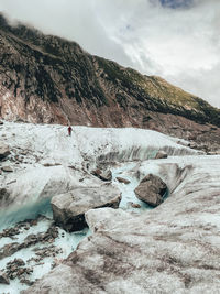Female hiker on glacier crossing a melt water river on mer de glace